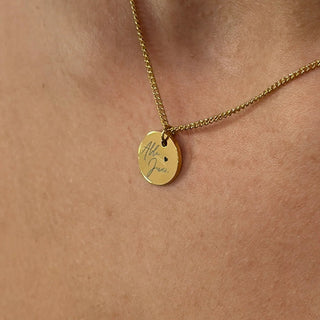 Gold necklace with a round pendant on a person's neck